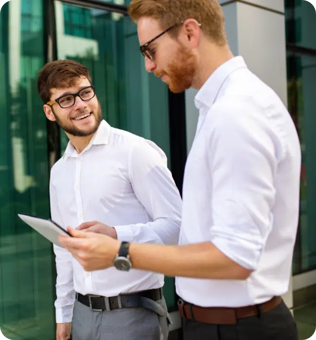 Two business men looking at tablet walking outside