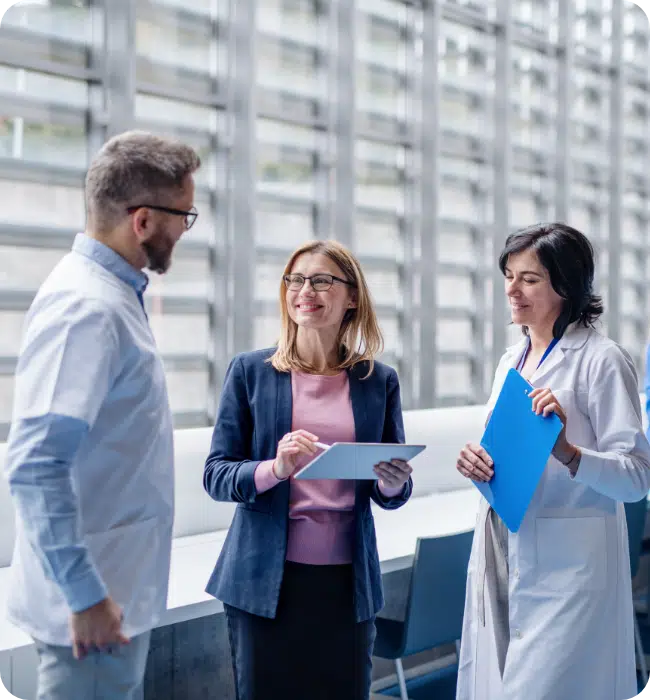 Industry individuals stood discussing in lab coats with clipboards.