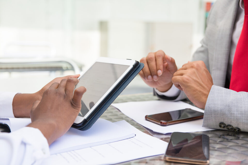 Business professionals reviewing information on a tablet during a meeting about enterprise consent platform migration.